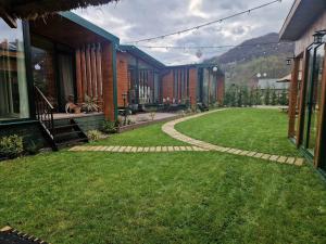 una casa con un patio de césped y una pasarela en Noor House Resort, en Şuncuiuş