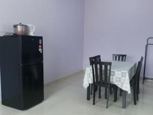 a dining room with a table and a black refrigerator at Annur Homestay 2 in Kampung Padang Maras