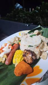 a plate of food with sausage corn and other foods at Gandah Forest Park Chalet in Kampong Bolok