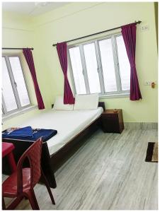a bedroom with a bed with purple curtains and a table at HOTEL PREMIUM PUJA Near Mandirpara JHEEL in Jādabpur +1 photo