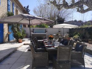 a table with chairs and an umbrella on a patio at MAS PROVENCAL A FLANC DE COLLINE in Bollène