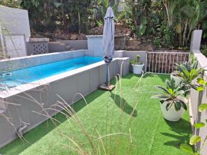 a small backyard with a swimming pool and grass at Close to the sea - Sea Facing Upstairs En-Suite Bedroom In Main House in Durban +7 photos