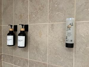 three bottles oficating products are on a tile wall at Plein Centre, luxueux 6 personnes, 2 chambres, parking , terrasse, vue époustouflante, Tout pédestre, piste à 100m in Isola