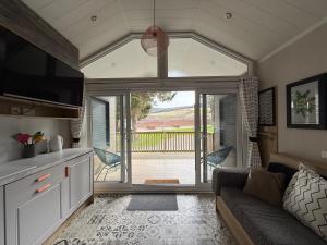 a living room with a couch and a large window at The Smolt Pod - Beautiful, luxury pod in Aberlour