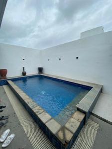 a large swimming pool in a white room with shoes on the floor at Villa Kila Rengganis Lombok in Prampuan +1 photo