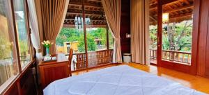 a bedroom with a bed in a room with windows at Moc Homestay & Villa in Cư Chinh