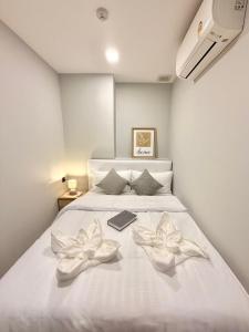 a bedroom with a white bed with two flowers on it at The Astra Sky River Chiang Mai 宜居4人 无边泳池 乳胶床垫 in Chiang Mai
