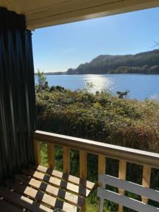 a porch with a bench and a view of a lake at The Secret Shepherds Hut- Off Grid Retreat in New Galloway