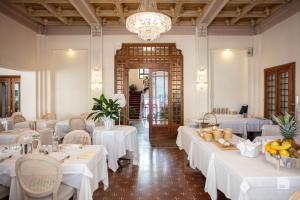 a restaurant with white tables and chairs and a chandelier at Hotel Villa Elena in Varazze