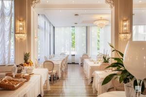a restaurant with white tables and chairs and windows at Hotel Villa Elena in Varazze