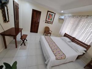 a bedroom with a bed and a desk and a piano at Sandybridge Eco Farm at Relly's Restaurant in Puerto Princesa City +15 photos