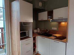a kitchen with white cabinets and a microwave at T2 Coeur d' Argelès-Gazost, tout à pied in Argelès-Gazost +8 photos