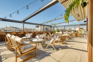 a patio with chairs and tables on a roof at Hotel America Barcelona in Barcelona