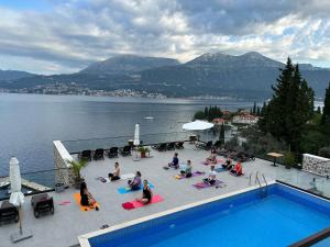 a group of people sitting around a swimming pool at Agape Rose Hotel in Tivat