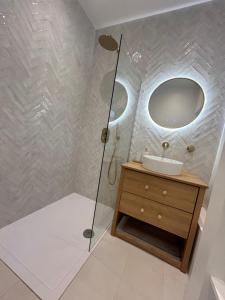 a bathroom with a shower with a sink and a mirror at Aeolian House in Cranleigh +8 photos