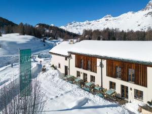 a building in the snow with snow covered mountains at Hotel Chesa Pool in Sils Maria