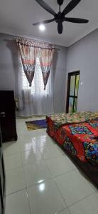 a bedroom with a bed and a ceiling fan at d'esaku homestay in Penaga