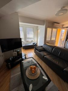 ein Wohnzimmer mit einem Ledersofa und einem Glastisch in der Unterkunft MATEA PREMIUM Apartment in Kragujevac