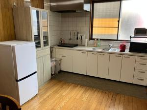 a kitchen with white cabinets and a white refrigerator at ジャンハウス in Takayama