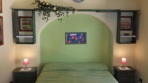 Un dormitorio con una cama verde con dos mesitas de noche. en Salina Acroeoliano monolocali in villa, en Leni