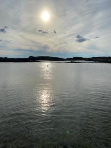 a large body of water with the sun in the sky at Ballyconneely house in Ballyconneely +2 photos