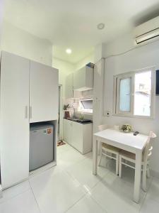 une cuisine blanche avec une table et un réfrigérateur dans l'établissement Happy Apartment, à Hô-Chi-Minh-Ville