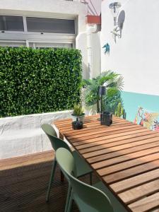 a wooden table with green chairs and a hedge at casa da vila 33 in Faro