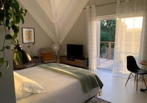 una camera da letto con un letto, una televisione e una finestra di The Studio in Knysna a Knysna