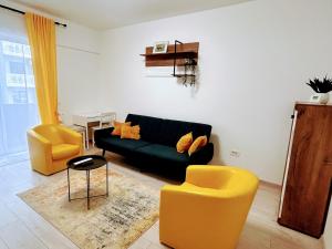 a living room with a black couch and two yellow chairs at Yellow Dawn Modern Flat in Quiet Area with Garage Parking and Self Check-In in Rediu