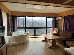 a bathroom with a tub and a couch and a table at Highland • Varjanisi in Batumi