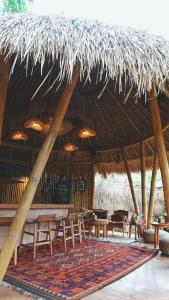 a restaurant with tables and chairs and a straw roof at Alpaca Lodge in Tanah Lot