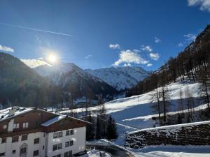 a building on a snowy mountain with the sun in the sky at Sonnenhotel Soldanella Sonneck in Samnaun +78 photos