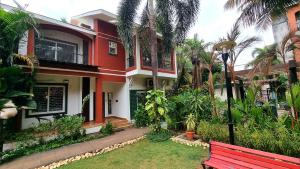 a red bench in front of a house with palm trees at Casa Bella - 4BHK Arpora JAQK Holidays in Arpora +47 photos