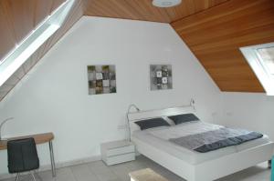 a white bedroom with a bed and a wooden ceiling at Ferienwohnung Sylvianne in Ottenhöfen