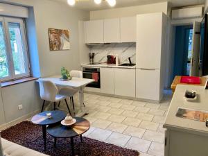 a kitchen with white cabinets and a table and chairs at 4 Châteaux Lastours Bijou 3 star Sudespine à 100m de los Castillos in Lastours