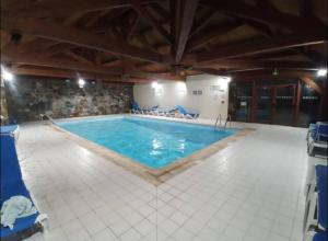 ein großer Swimmingpool mit blauen Stühlen drumherum in der Unterkunft Le fleuri ensoleillé de Guzet in Ustou