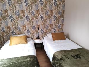 two beds in a small room with a wallpaper at La Gigotière, 5mn du ZooParc de Beauval in Noyers-sur-Cher