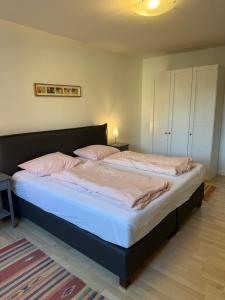 a bedroom with a large bed with white sheets and pink pillows at Apartment 4 in Wyk auf Föhr