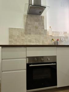 una cocina con armarios blancos y horno negro en Stay in Triana, en Sevilla 9 fotos más