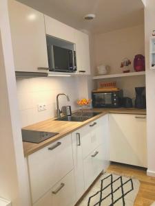 a kitchen with white cabinets and a sink and a microwave at Le Bassin à vos pieds avec T2 Élégant entre Plage et Hyper Centre in Arcachon +19 photos