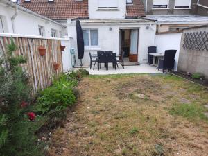 a backyard with a table and chairs and a fence at Maison Chez Lili à 200 m de la plage ,jardin privé et clos in Gravelines