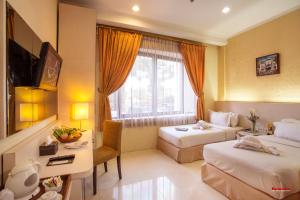 a hotel room with two beds and a desk at Ros-In Hotel in Yogyakarta