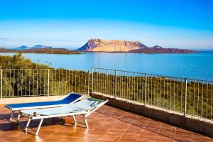 een bank op een patio met uitzicht op het water bij Villino Caddu in San Teodoro