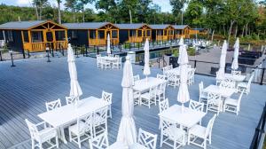 a deck with white tables and umbrellas in front of a building at CHICKADEE LIMIT 4 in North Sebago