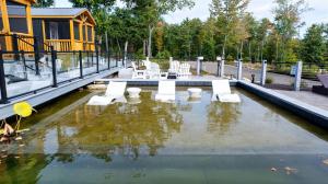 a pool of water with white chairs and a house at CARDINAL LIMIT 3 in North Sebago