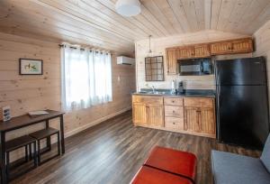 a kitchen with a black refrigerator and wooden cabinets at CARDINAL LIMIT 3 in North Sebago