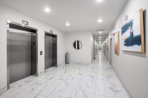 a hallway with white walls and silver doors and marble floors at Luxury 1br Nolibs Pool Access in Philadelphia