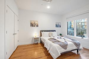 a white bedroom with a large bed and a window at Luxury 1br Nolibs Pool Access in Philadelphia
