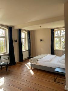 ein Schlafzimmer mit einem großen Bett und zwei Fenstern in der Unterkunft An Den Wiesen Gasthaus am Finowkanal in Wandlitz