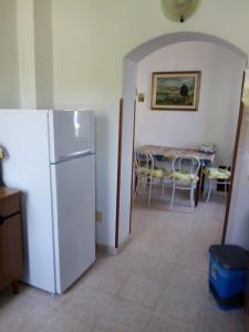 a kitchen with a white refrigerator and a table with chairs at Villa Mirabelli in Tropea